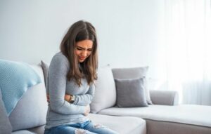 Woman having painful stomachache on bed